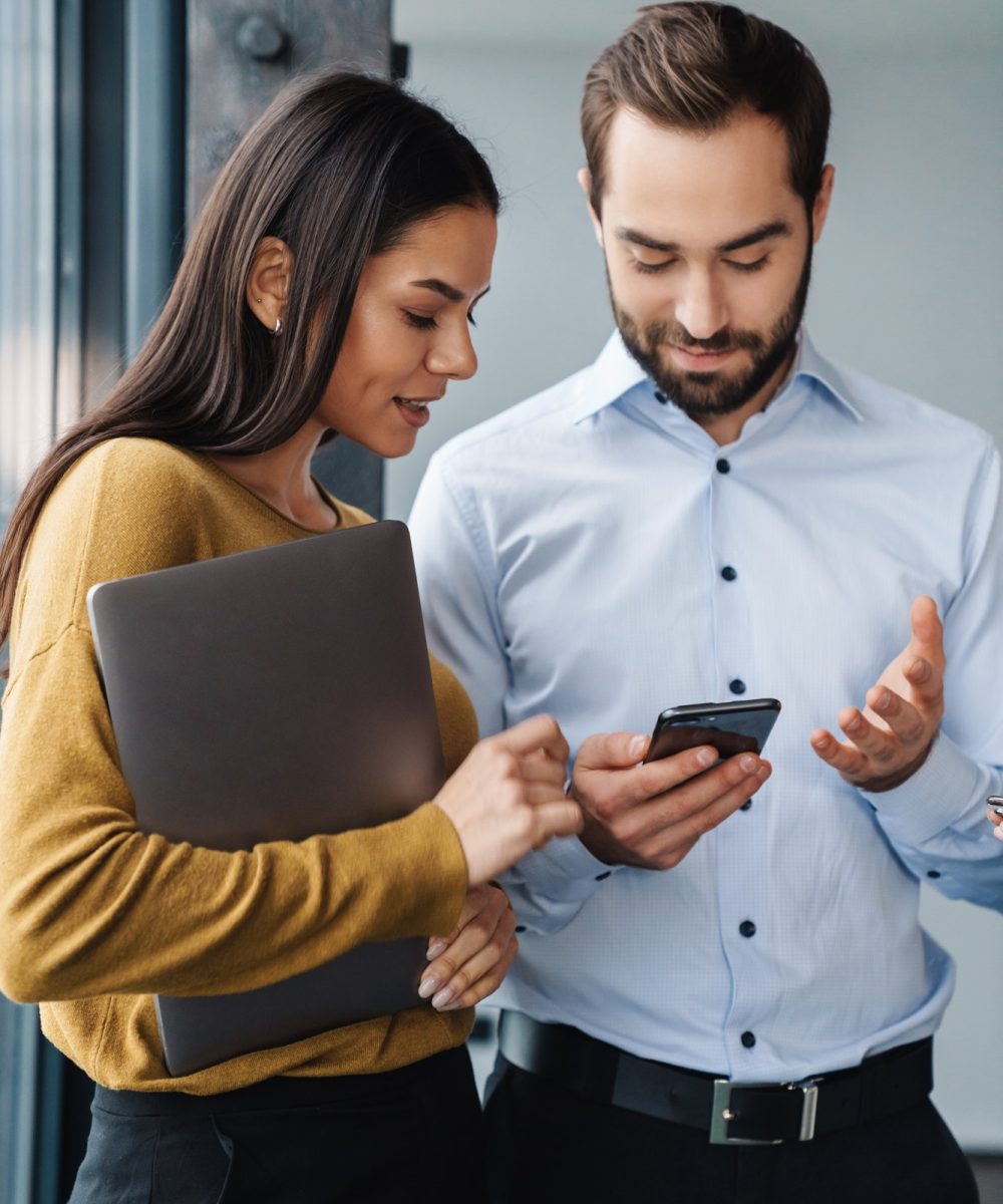 portrait-of-colleagues-talking-and-using-cellphone-while-working-in-office.jpg